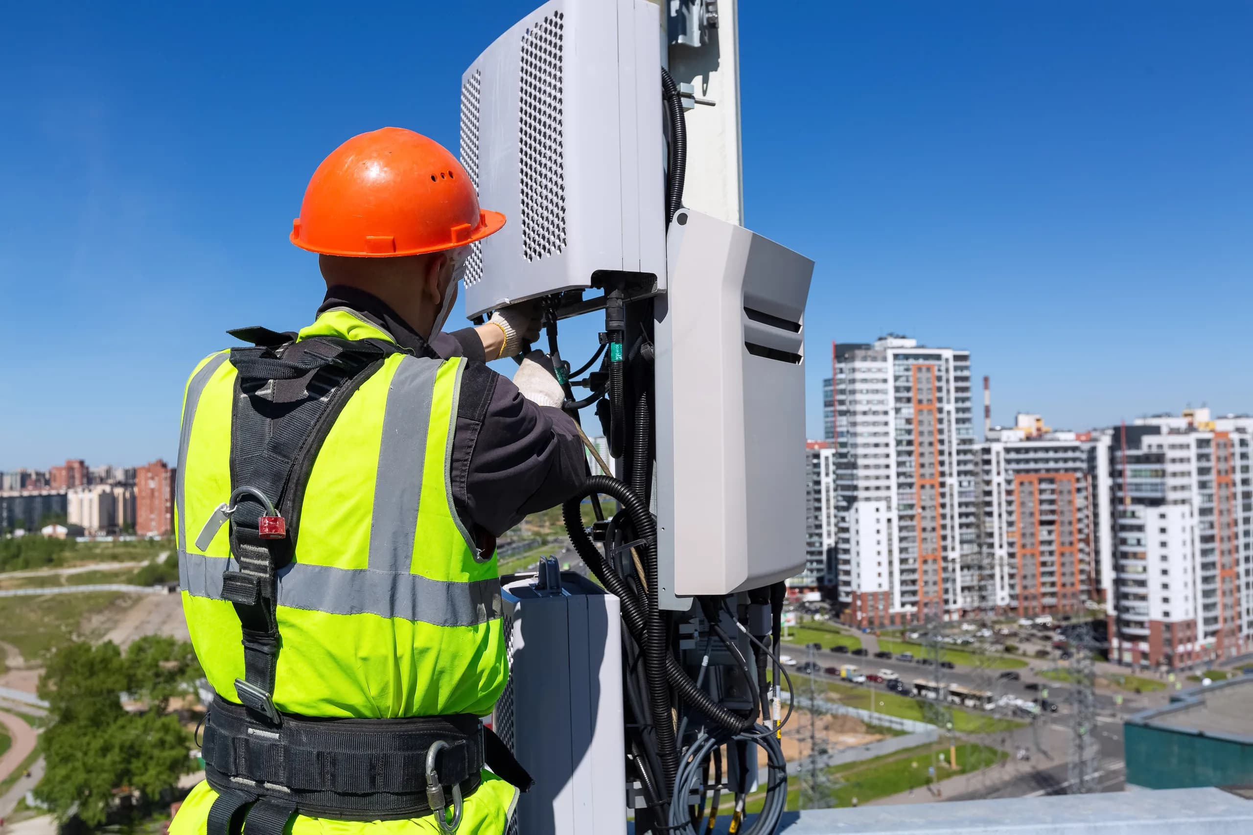 A technician installs a radio repeater on a mast